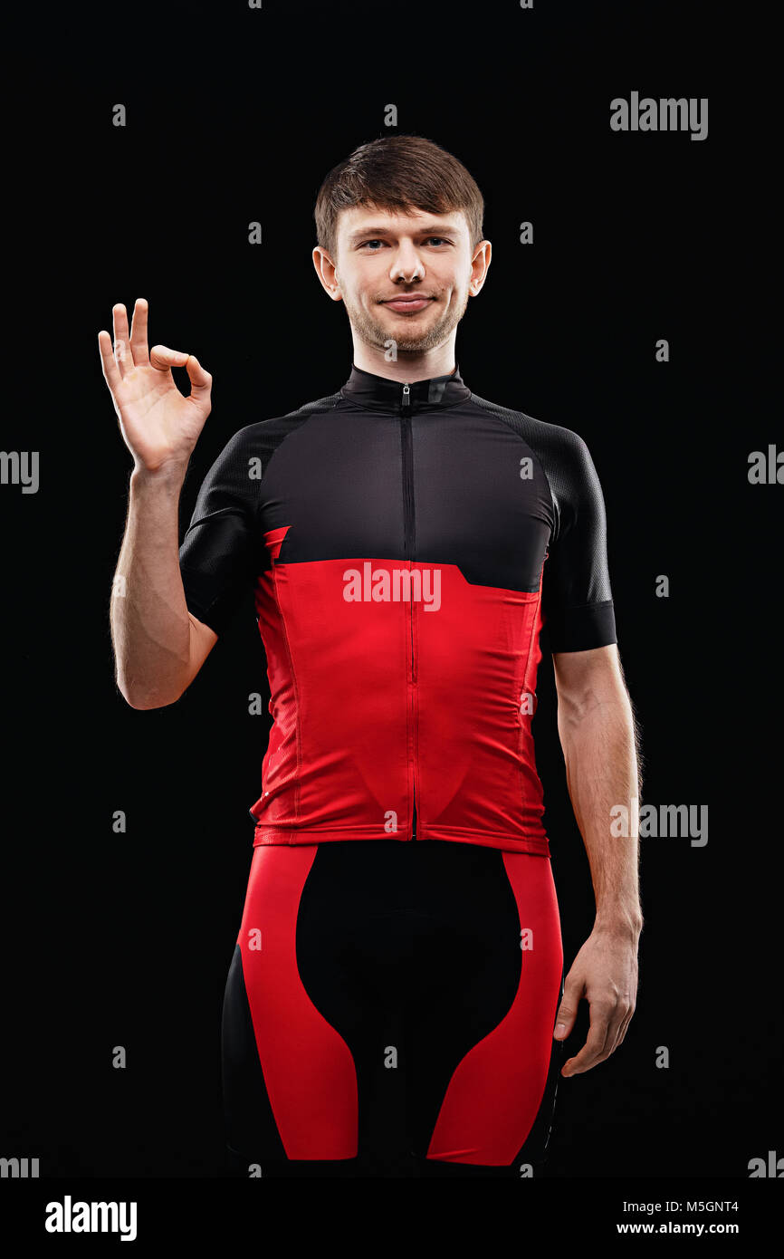 Sport. Cyclist in training clothes on black background shows OK sign. Stock Photo