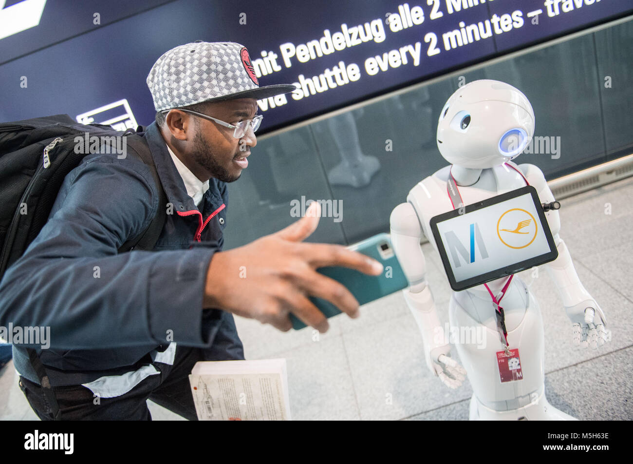 Munich, Germany. 20th Feb, 2018. Robot Josie Pepper assists passenger Nadio Garrido from Angola at the airport in Munich, Germany, 20 February 2018. Pepper is a humanoid robot programmed to analyse and emulate human gestures and facial expressions. Credit: Lino Mirgeler/dpa/Alamy Live News Stock Photo