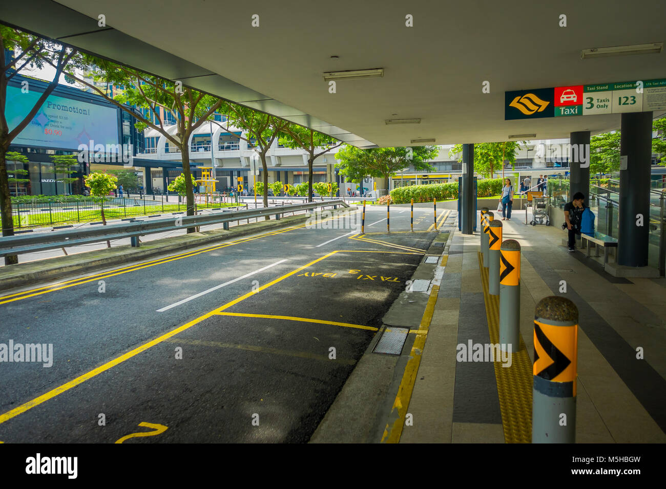 SINGAPORE, SINGAPORE - JANUARY 30, 2018: Outdoor view of parking area at outside of a building with some unidentified people walking in the sidewalks  Stock Photo