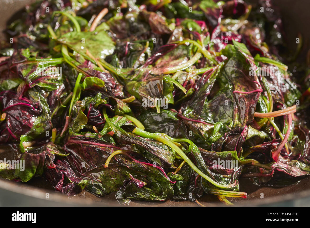 Red Amaranth, a type of spinach popular in Asian cuisines, cooked in a wok Stock Photo