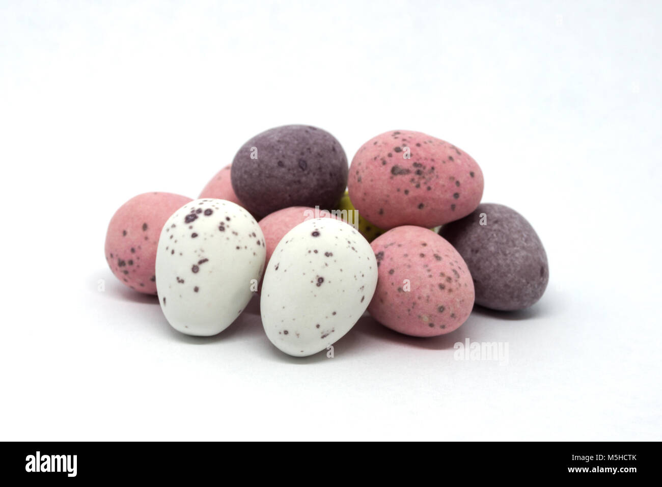 Ten Chocolate Candy covered Easter Eggs in a pile and isolated on a white background. The eggs at the front of the mage are in full focus and gradualy Stock Photo
