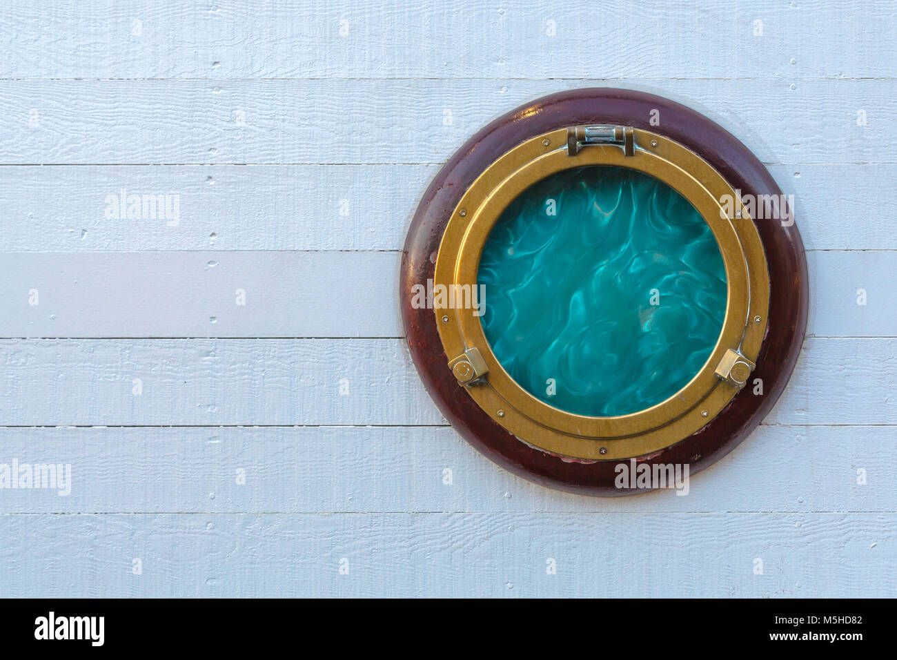 Ship window or porthole on white wooden wall. Stock Photo