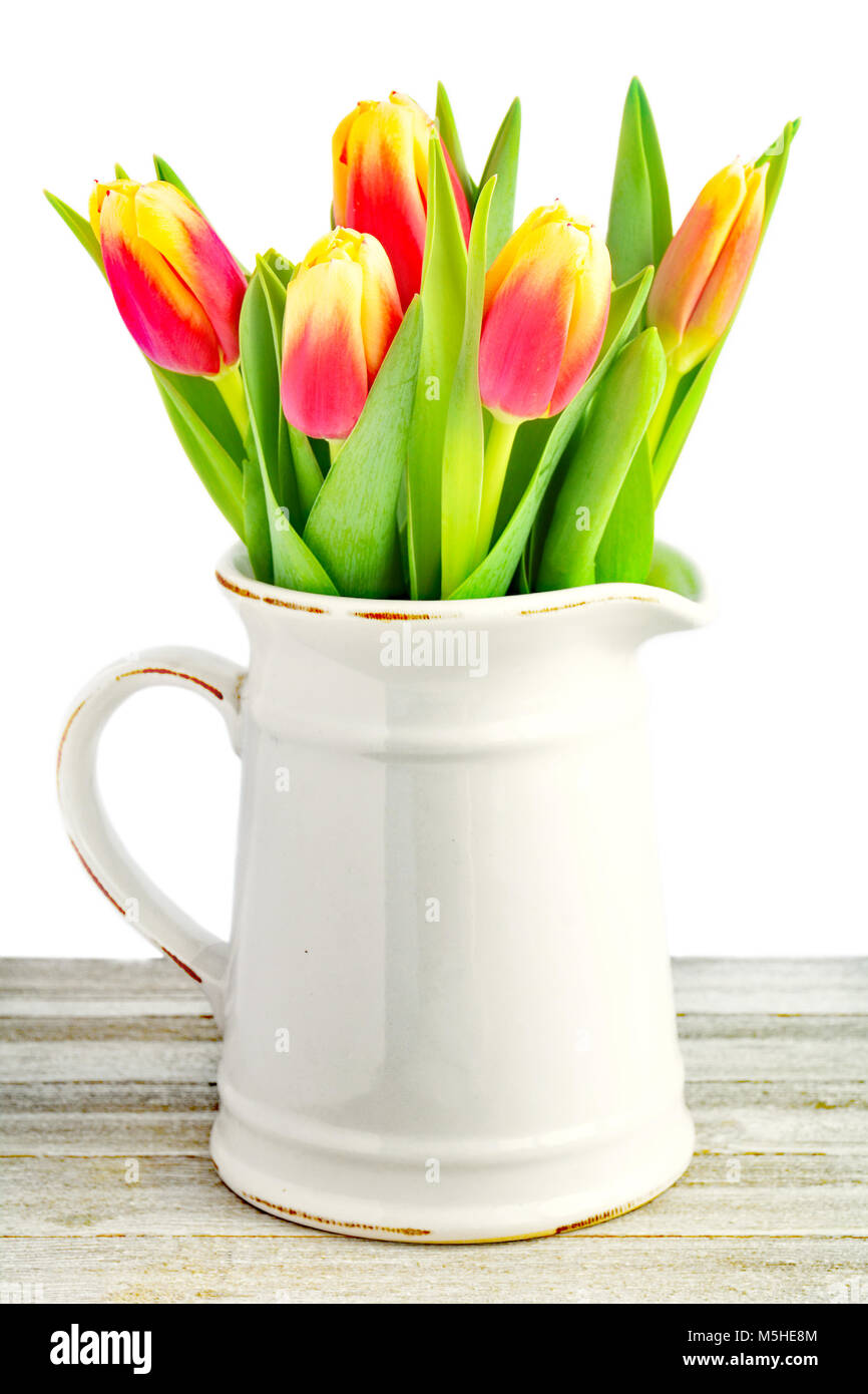 Red and yellow tulips in old fashioned ceramic jug in vertical format ...