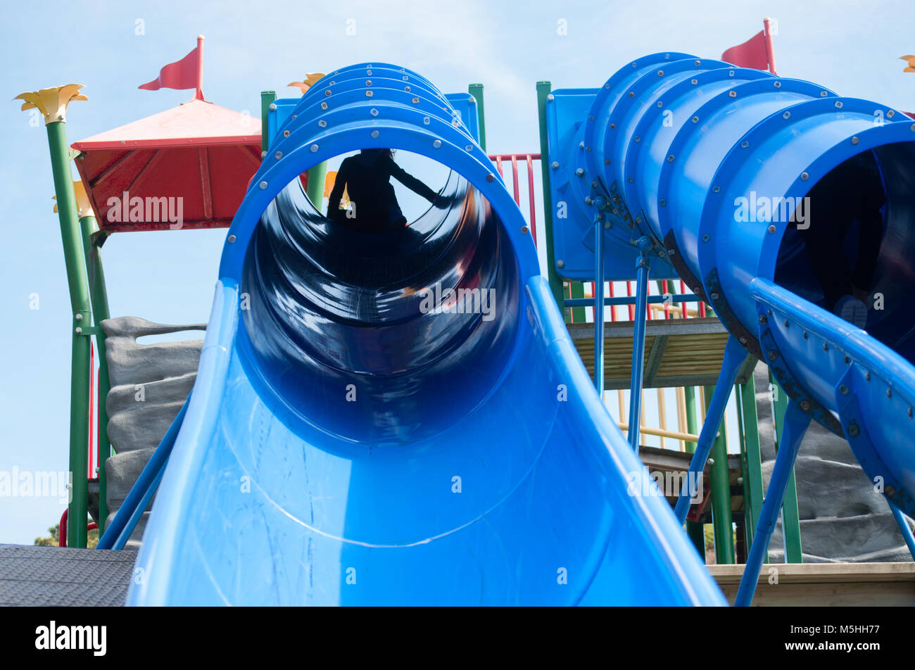 Child Coming Down A Blue Slide In The Playground Stock Photo
