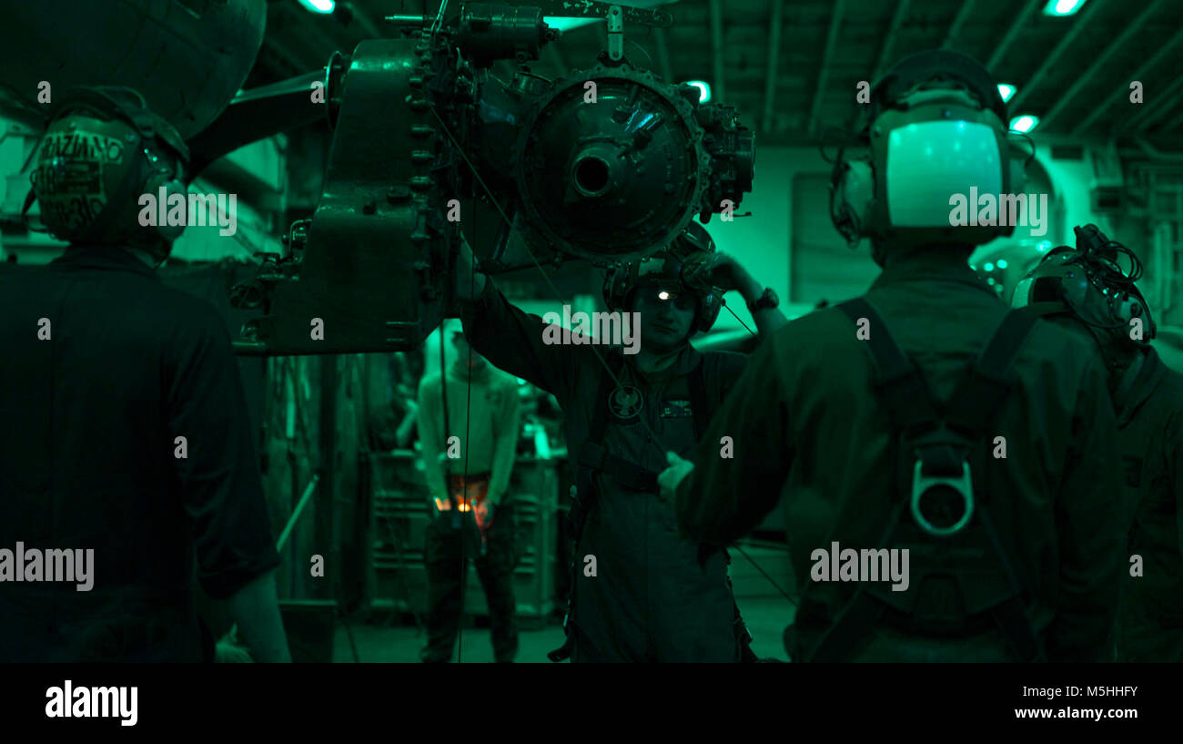 ATLANTIC OCEAN (Feb. 13, 2018) Sailors and Marines aboard the amphibious assault ship USS Iwo Jima use an aviation bridge crane to lower a tilt axis gearbox in the ship’s hangar bay. The Iwo Jima Amphibious Ready Group (ARG) is deployed in support of maritime security operations and theater security cooperation efforts in Europe and the Middle East.  The Iwo Jima ARG embarks the 26th Marine Expeditionary Unit and includes Iwo Jima, the amphibious transport dock ship USS New York (LPD 21), the dock landing ship USS Oak Hill (LSD 51), Fleet Surgical Team 8, Helicopter Sea Combat Squadron 28, Tac Stock Photo