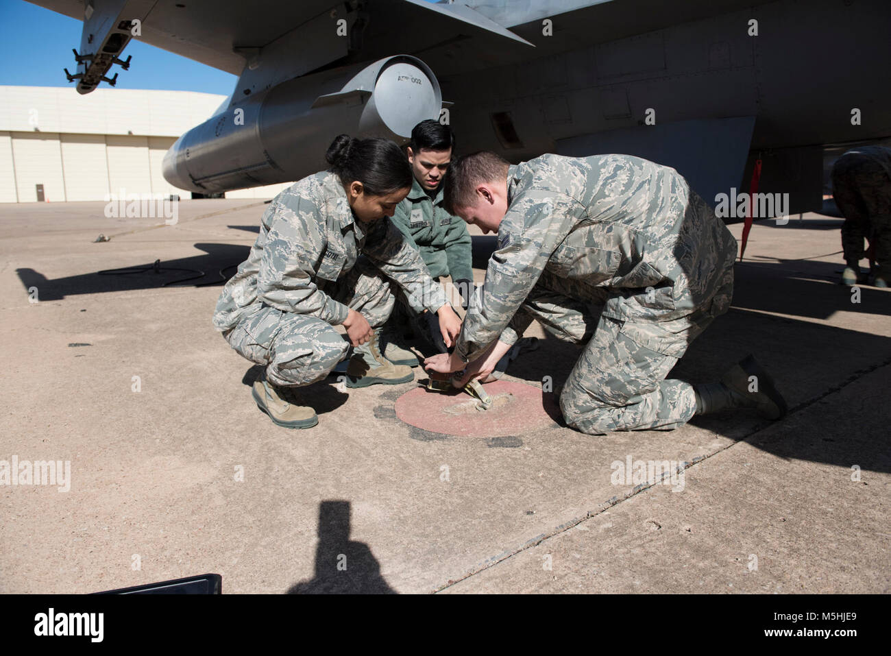 Senior Airman Jeremiah Castro, Airman 1st Class Wesley Knott and Airman Hasany Gotay, 362nd Training Squadron crew chief apprentice course students, tie down an F-16 Falcon at Sheppard Air Force Base, Texas, Feb. 2, 2018.  Crew chief students are taught to tie down air craft to secure for high winds.  Castro, Knott and Gotay are in block five of nine and scheduled to graduate April 2. Stock Photo