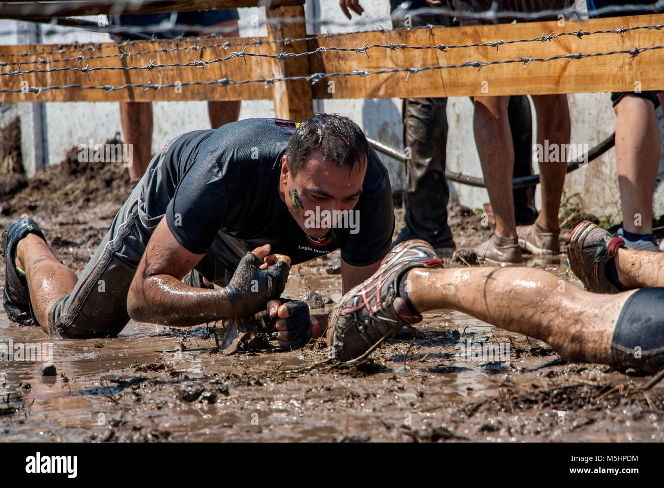 A man crawling under barbed wire during strength race Legion Run held ...