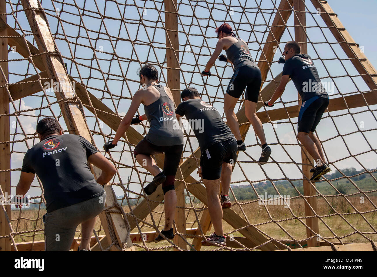 A team of men and women climbing a cargo net at the strength race Legion Run held in Sofia, Bulgaria on 26 July 2014 Stock Photo