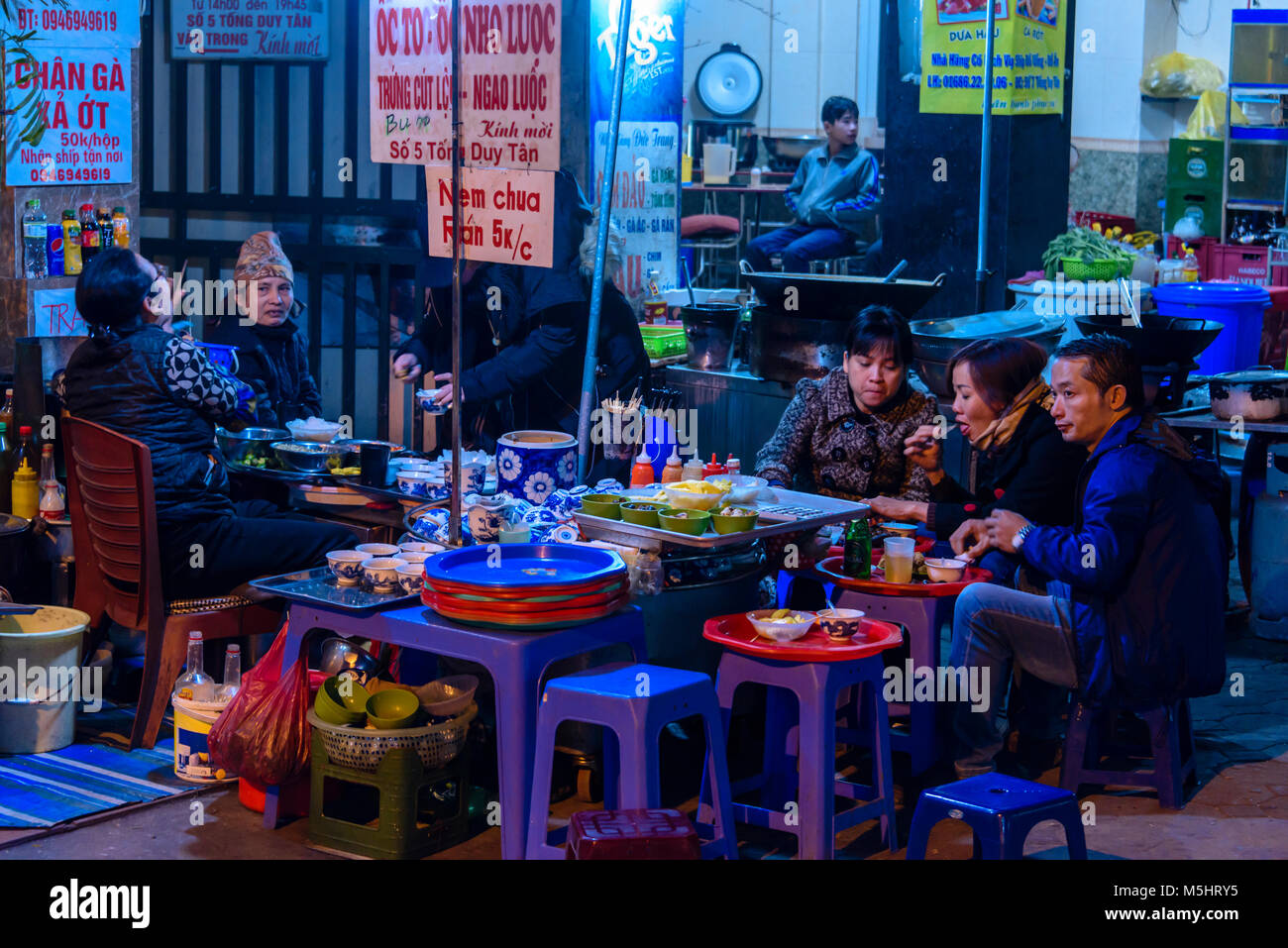 Men eating at a traditional Vietnamese street food pop-up cafe in Hanoi, Vietnam. Stock Photo