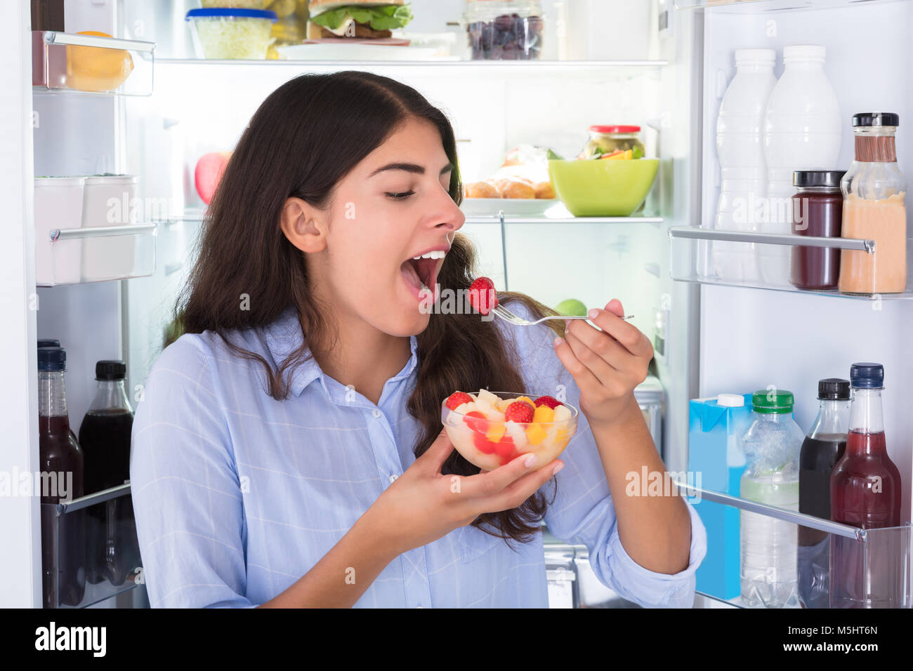 Close-up Of A Young Woman Eating Fresh Fruits In Bowl Stock Photo