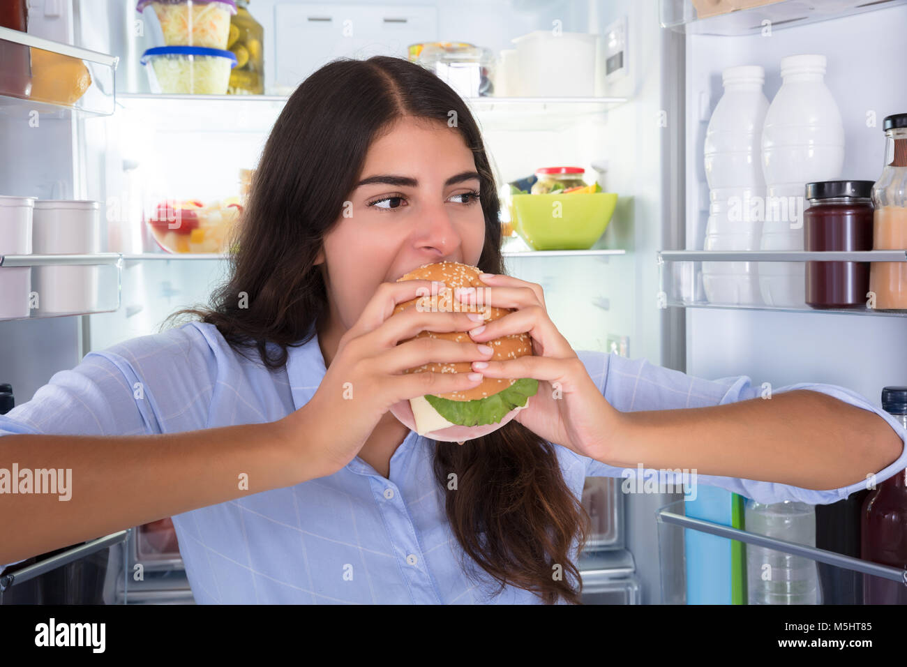 Portrait Of A Young Happy Woman Eating Burger Stock Photo