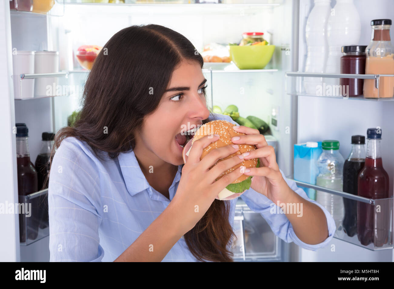 Portrait Of A Young Happy Woman Eating Burger Stock Photo