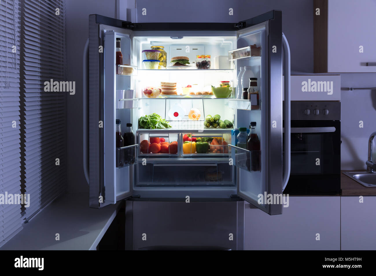 Open Refrigerator Full Of Juice And Fresh Vegetables In Kitchen Stock