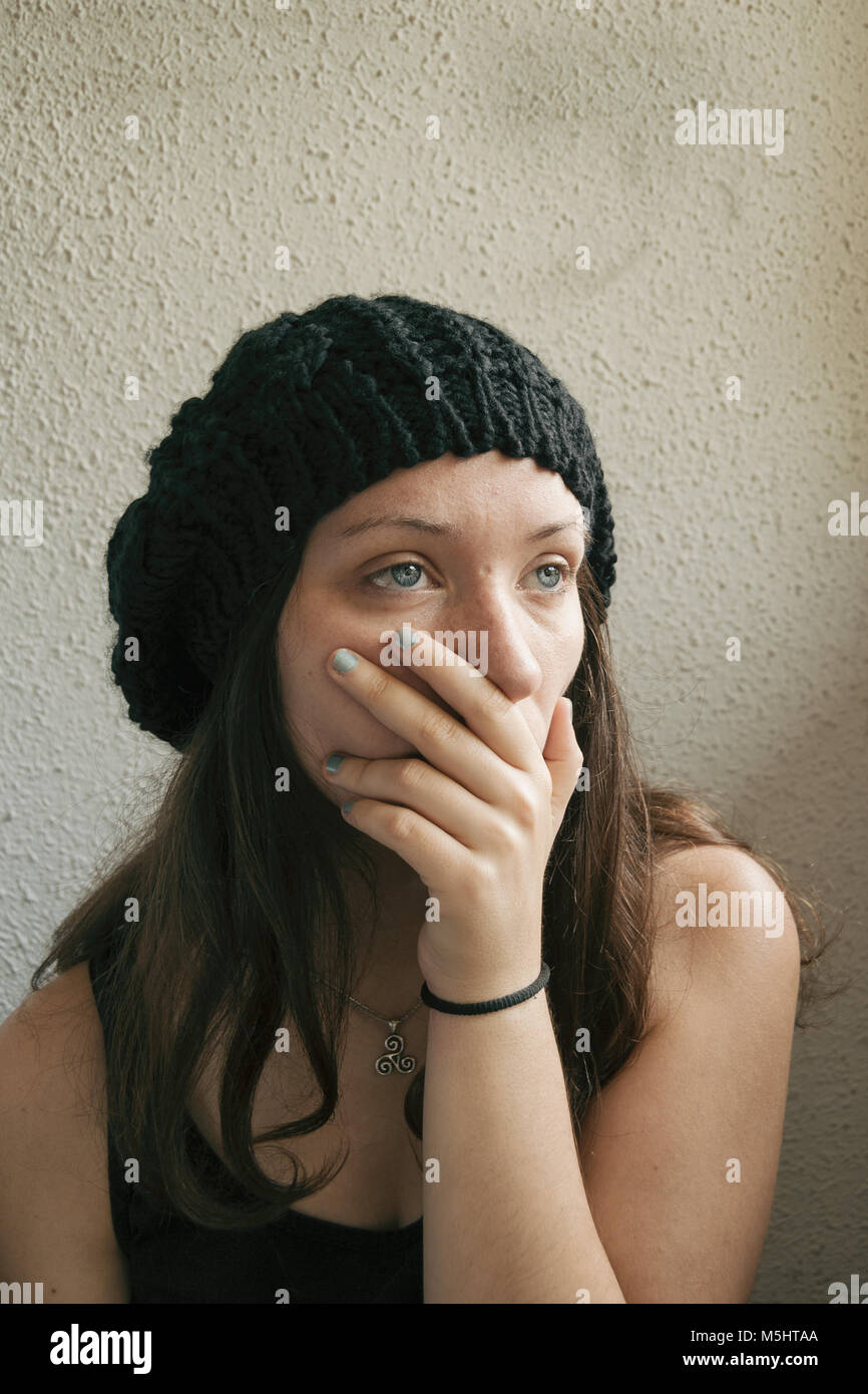 girl with long hair and blue eyes covering her mouth with her hand Stock Photo