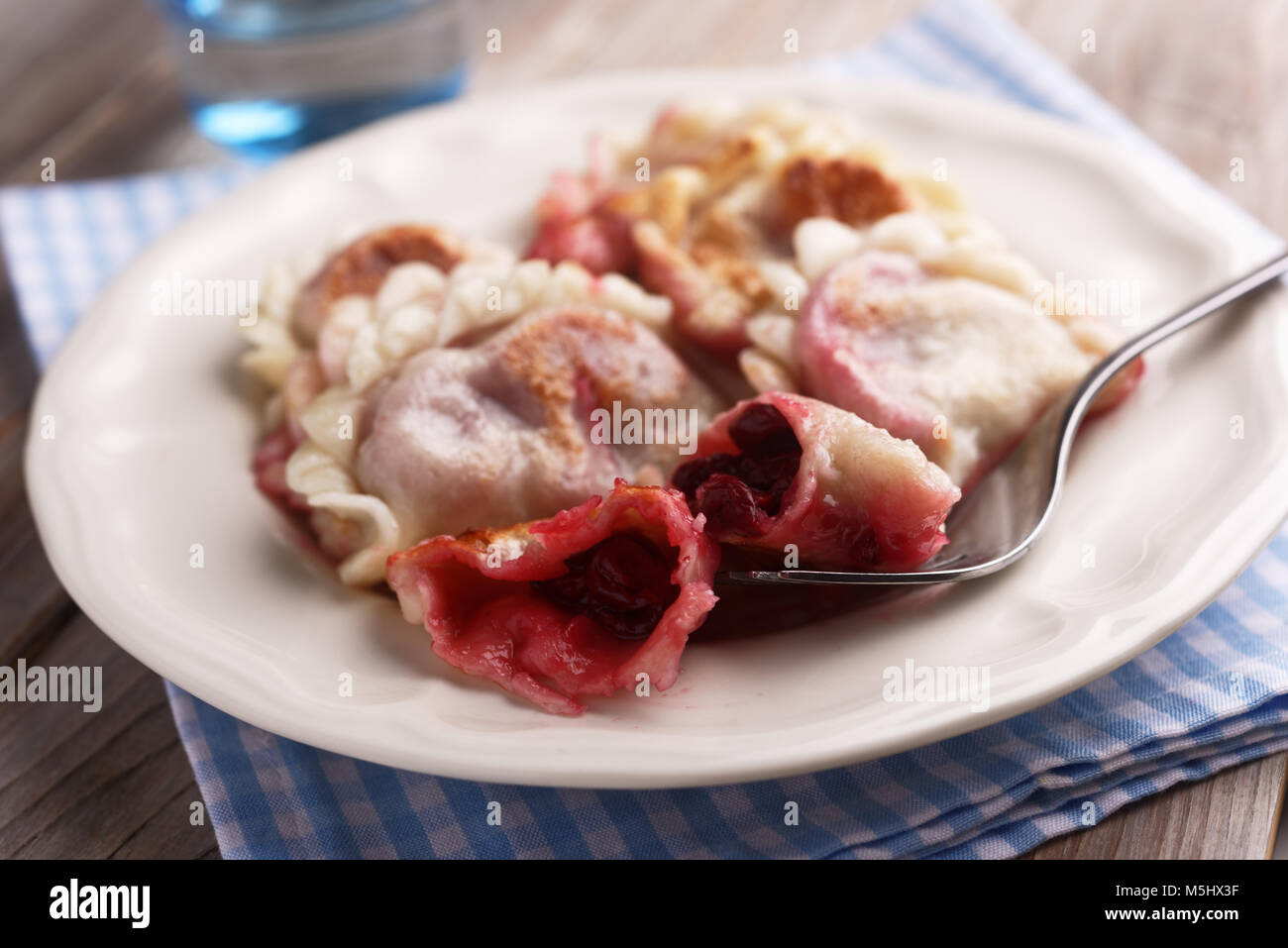 Traditional Polish dumplings Pierogi ruskie with sour cherry on a rustic table Stock Photo