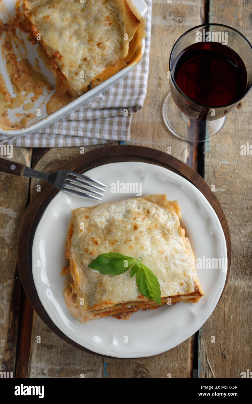 Lasagna Bolognese and red wine on a rustic table Stock Photo Alamy