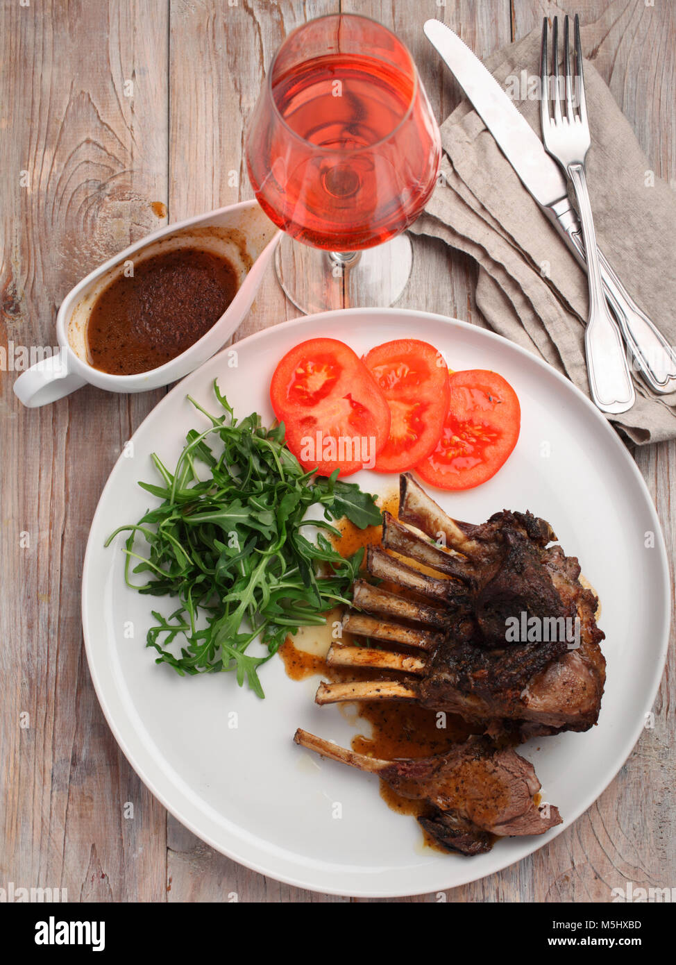 Roasted lamb ribs with rocket salad and tomato on a rustic table Stock ...