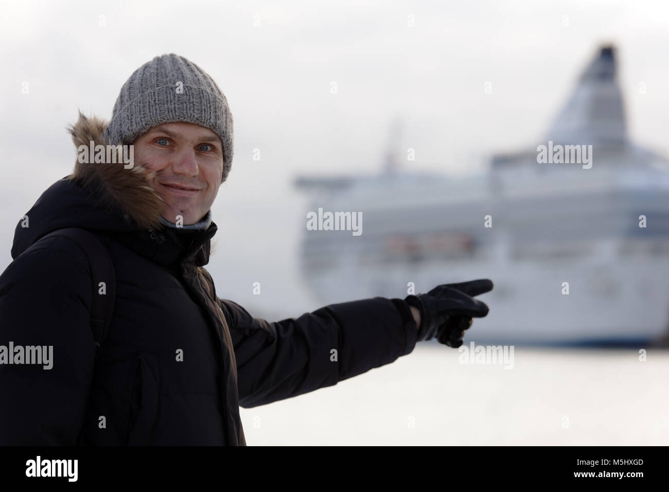 Mature man in winter clothes pointing to a cruise ship Stock Photo