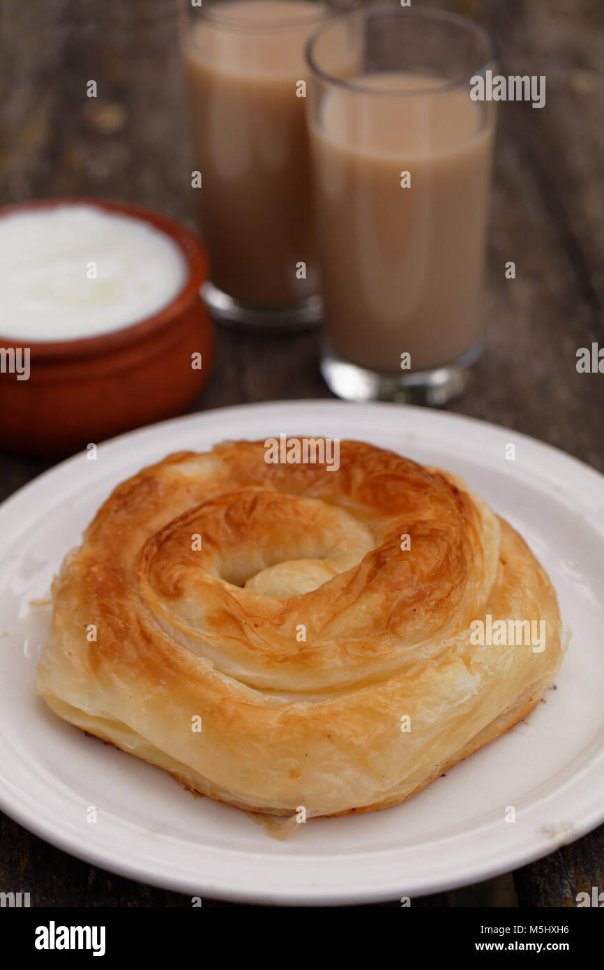 Traditional Bulgarian pastry Banitsa on a rustic table with Greek