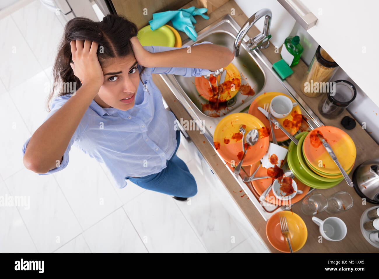 Frustrated Young Woman Standing Near Messy Utensils On Countertop In Kitchen Stock Photo
