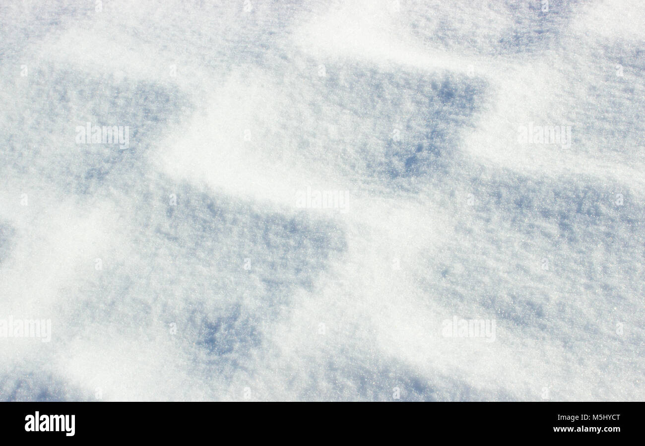 Background with snowy pavement with shadow. Under the snow is the pavement and its outlines are rising in the shining snow. The snow sparkles in the s Stock Photo