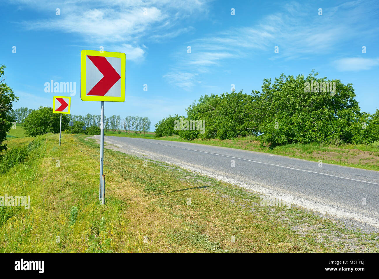 Warning signs for dangerous turn on country road. Stock Photo