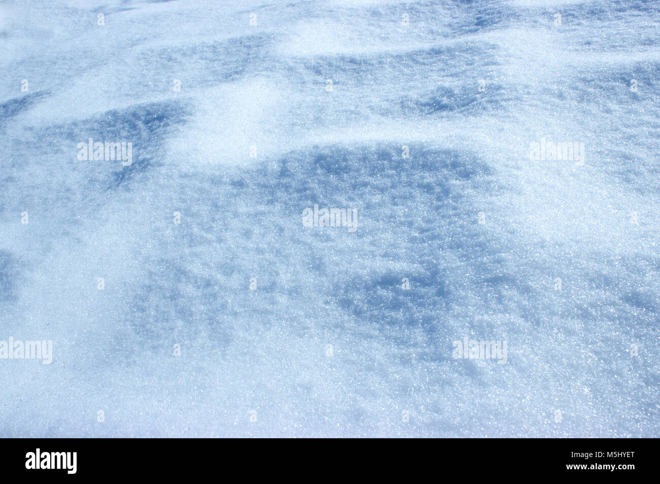 Background with snowy pavement with shadow. Under the snow is the pavement and its outlines are rising in the shining snow. The snow sparkles in the s Stock Photo