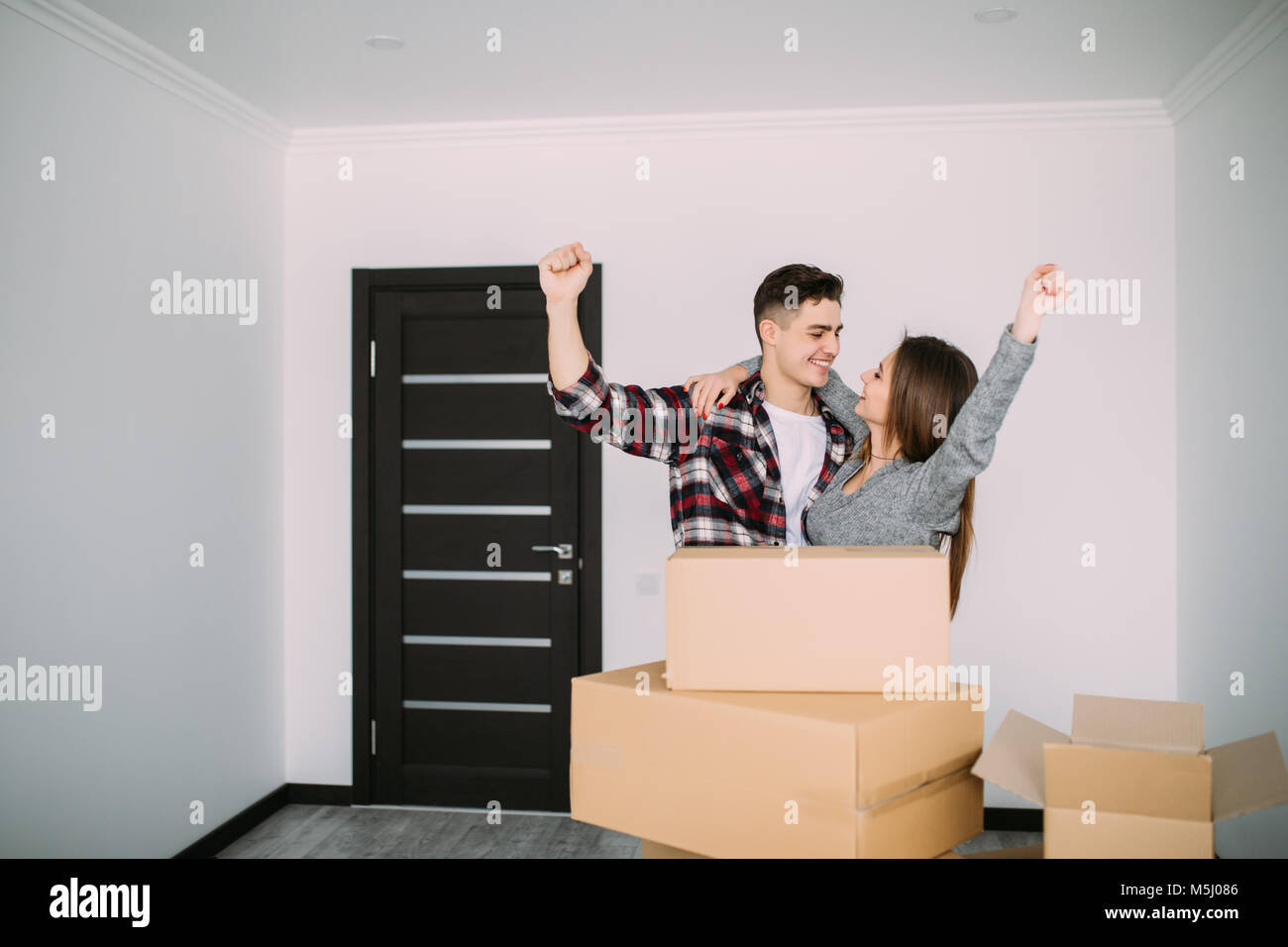 cheerful and happy young couple of their new home with moving cardboard ...