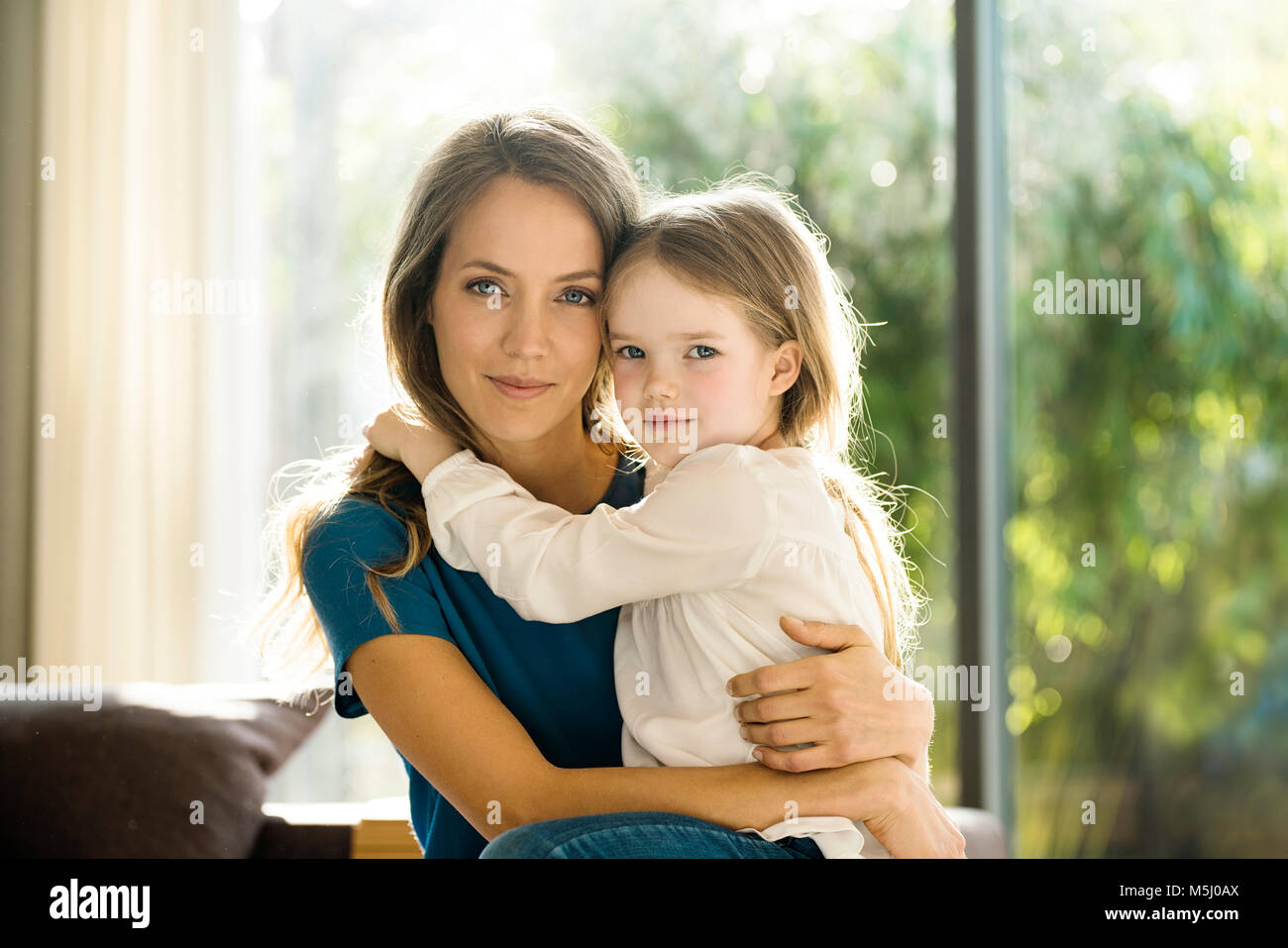 Portrait of smiling mother holding her daughter at home Stock Photo