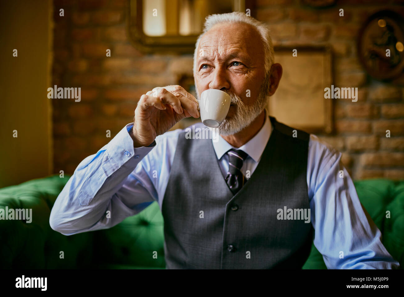 Elegant senior man drinking coffee in a cafe Stock Photo