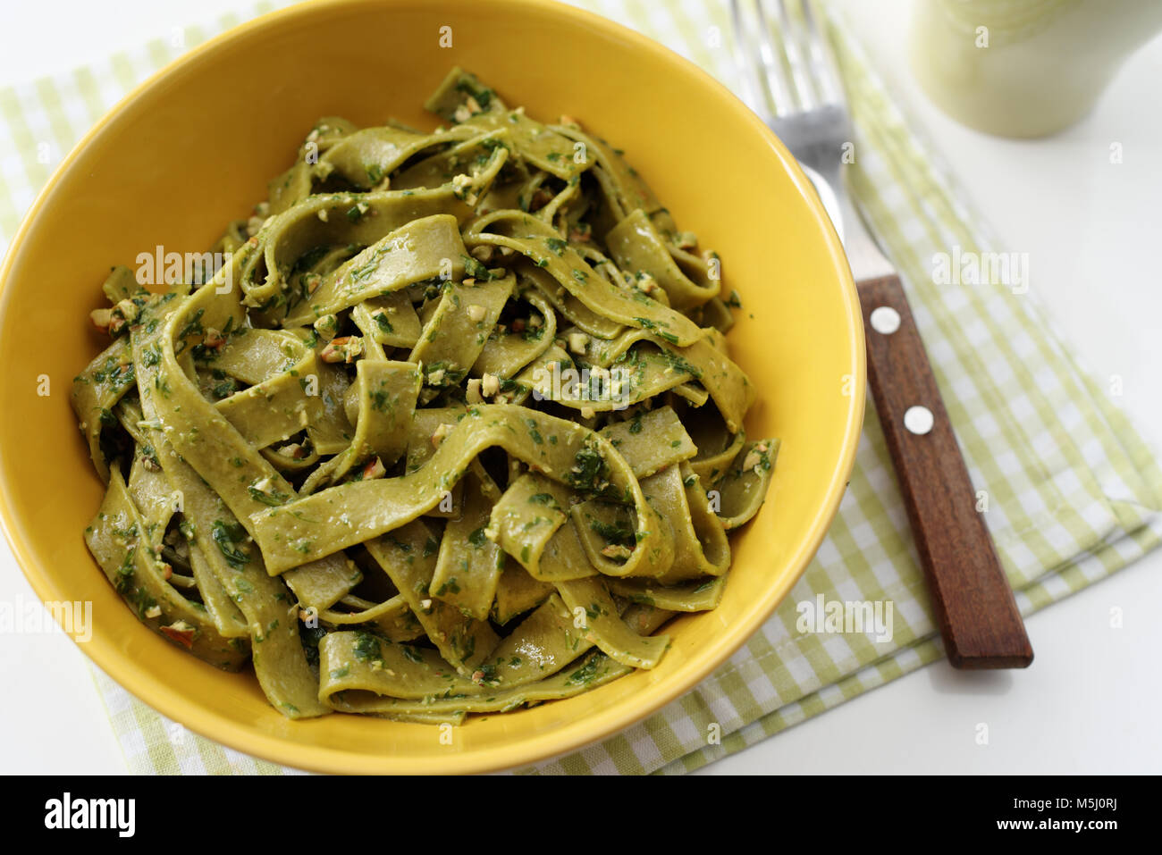 Spinach pasta with pesto sauce in a yellow bowl Stock Photo