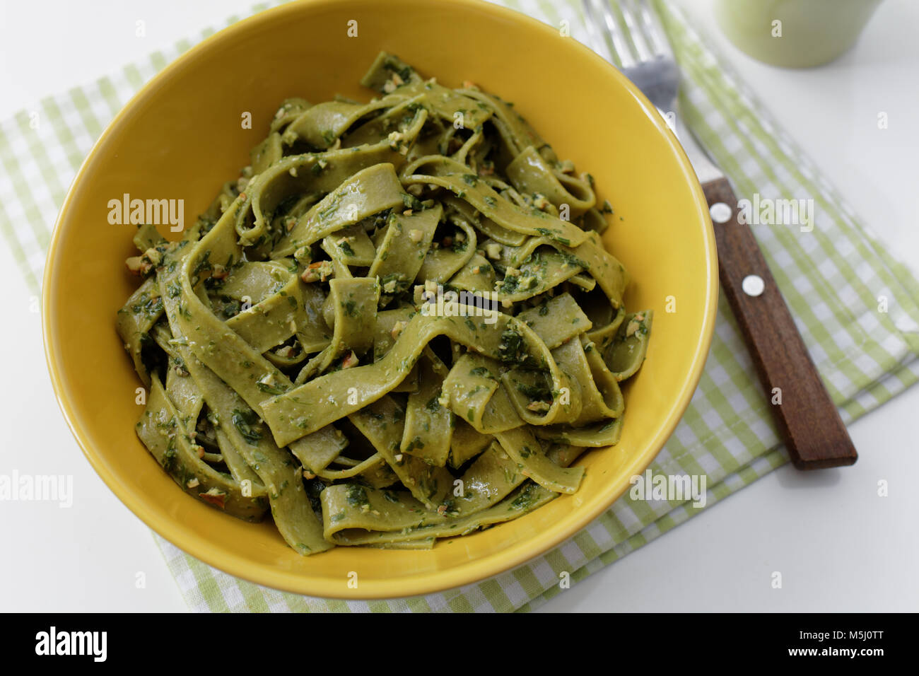 Spinach pasta with pesto sauce in a yellow bowl Stock Photo