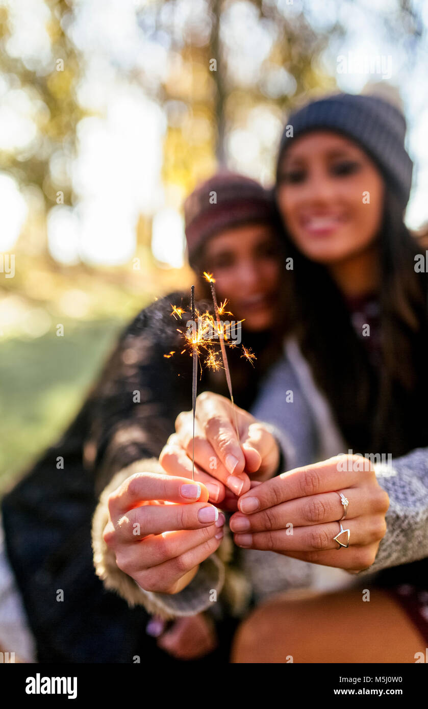 Two gorgeous women having fun with sparklers in an autumnal forest Stock Photo