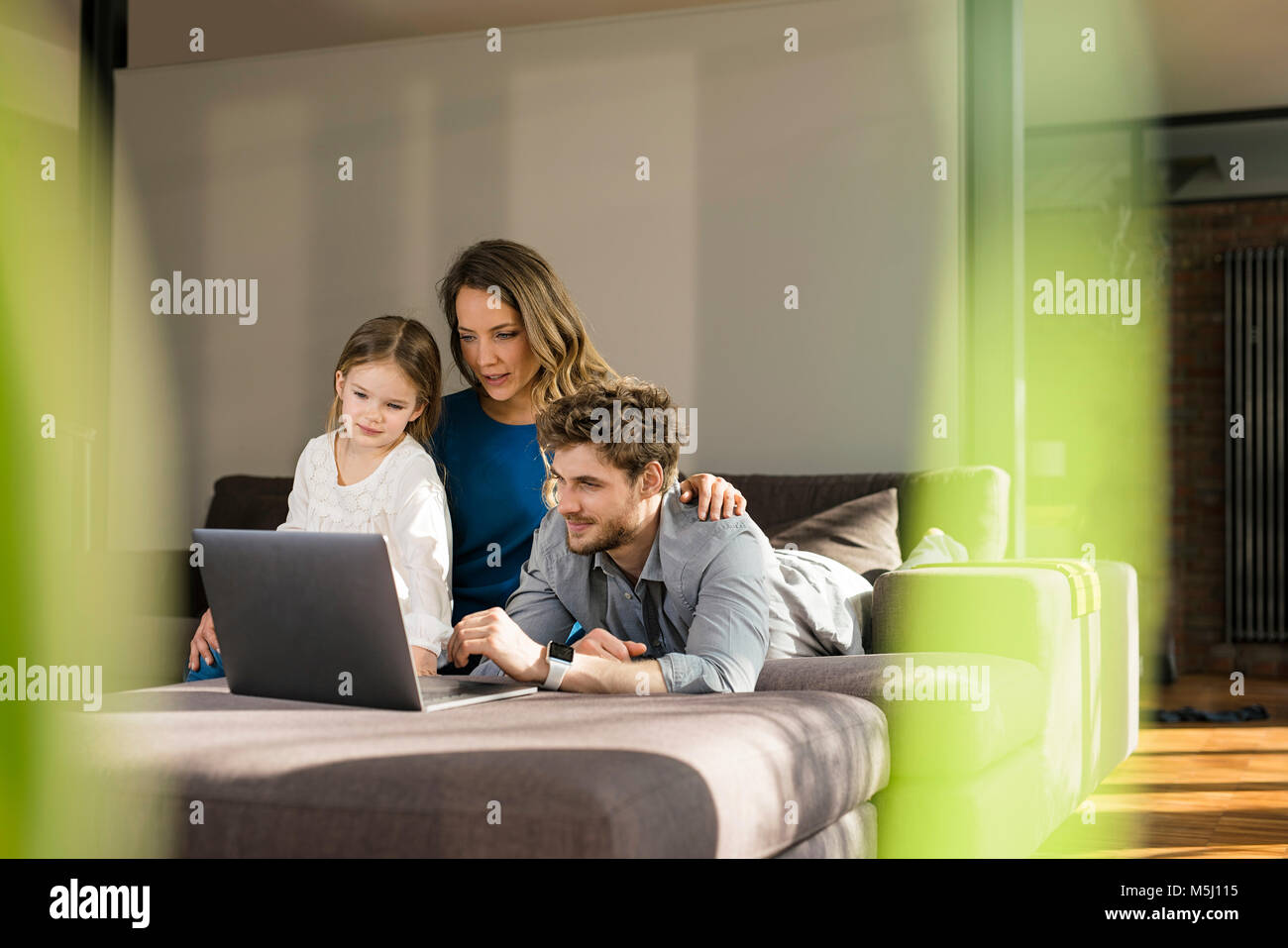 Family using laptop on sofa at home Stock Photo