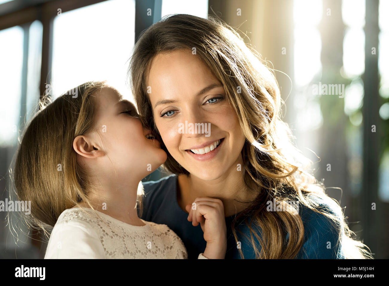 Smiling girl whispering into her mother's ear Stock Photo