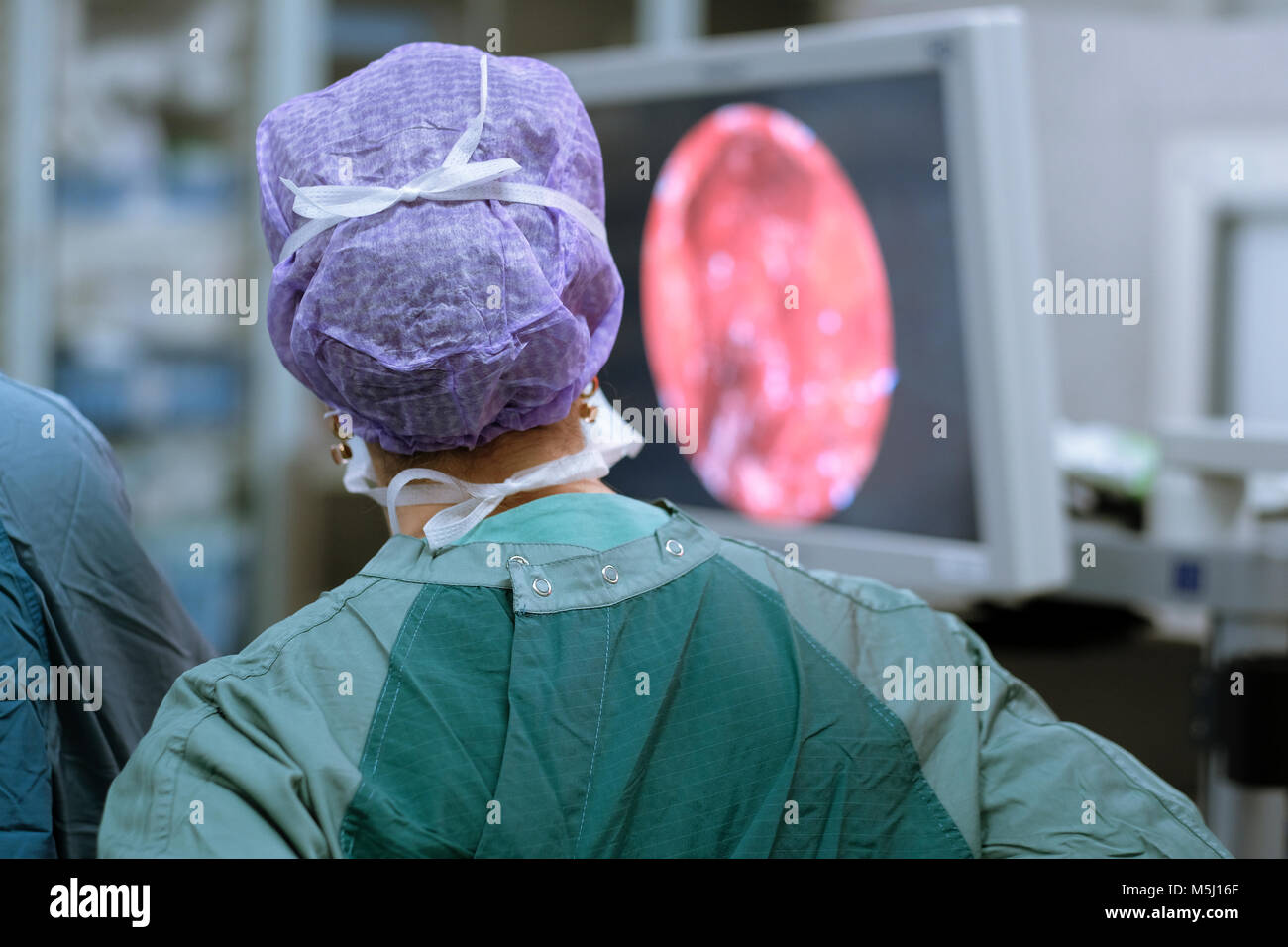 Neurosurgeon in scrubs looking at monitor Stock Photo