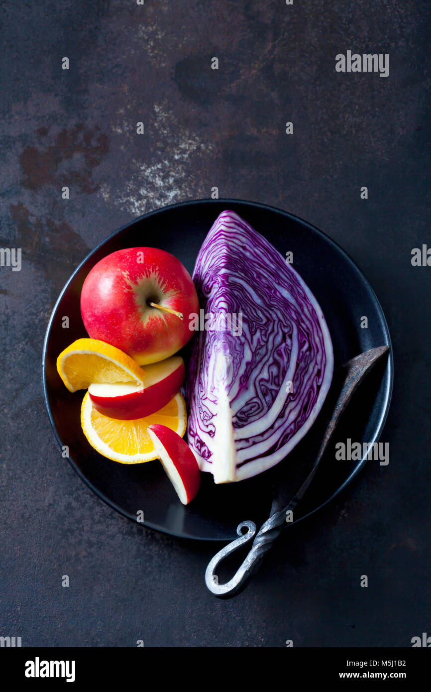 Bowl of sliced red cabbage, apples and orange slices Stock Photo
