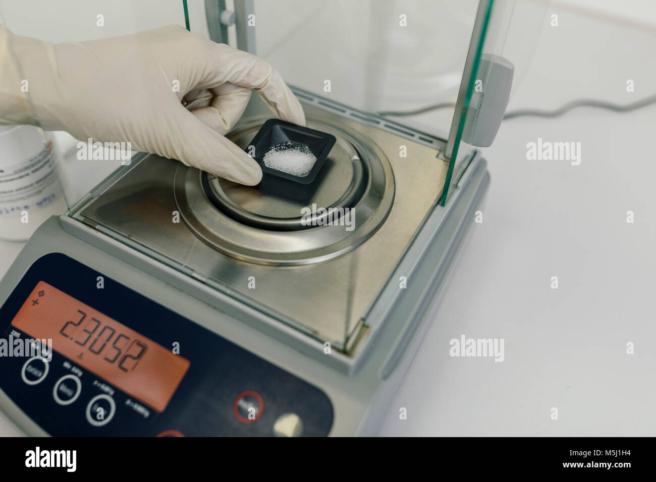Hand with protective glove using scales in laboratory of a pharmacy Stock Photo