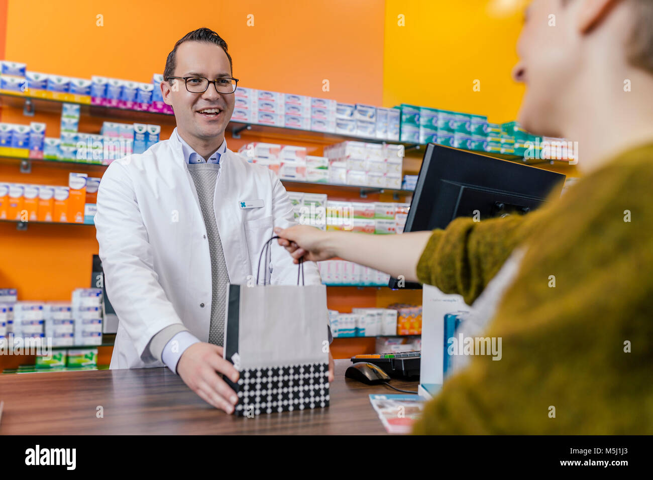 Pharmacist giving bag with medicine to customer in pharmacy Stock Photo ...