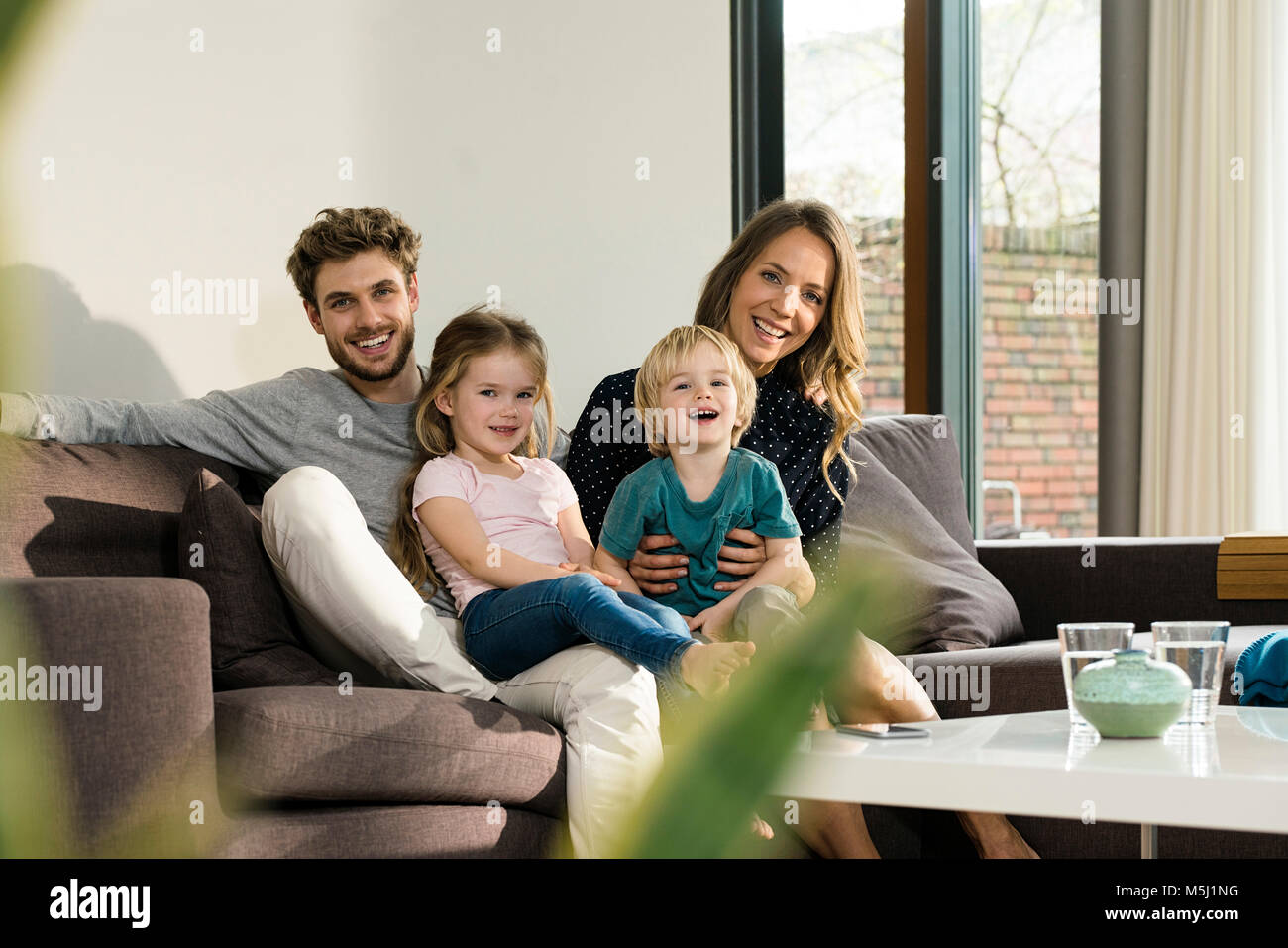 Portrait of happy family sitting on sofa at home Stock Photo