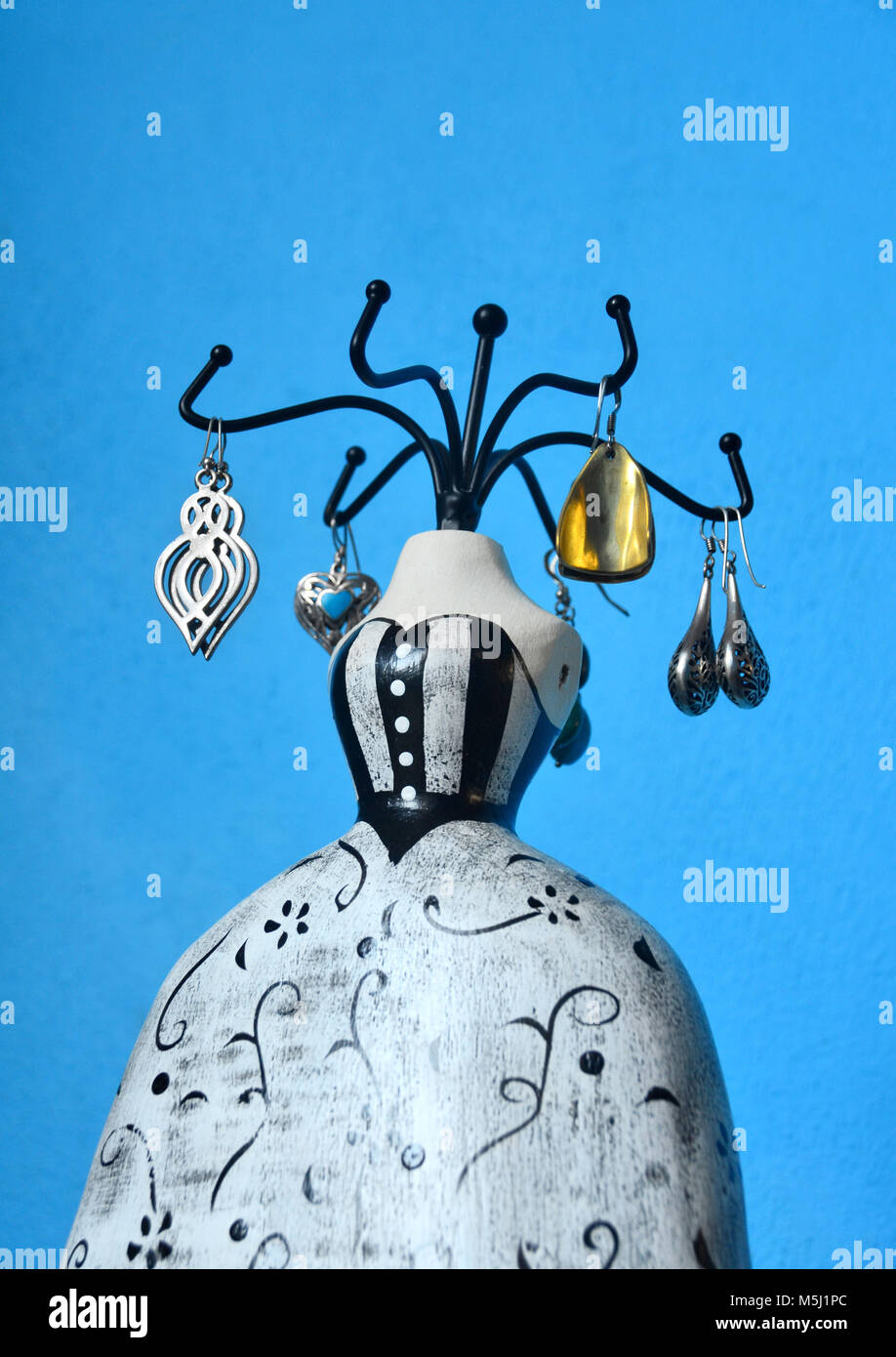 A painted lady mannequin jewellery stand with a display of earrings. Stock Photo