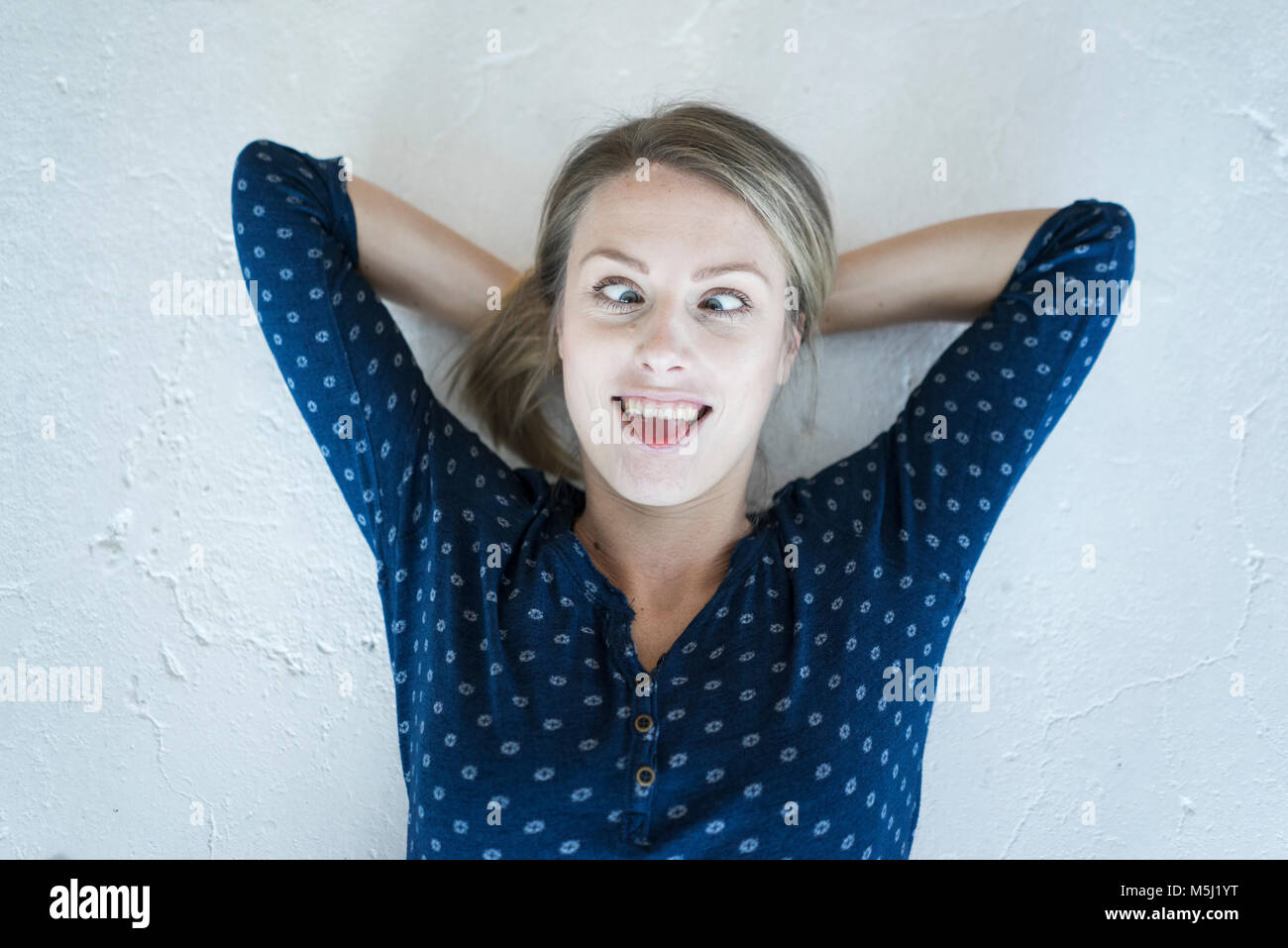 Portrait of young woman lying on the floor pulling funny faces Stock Photo