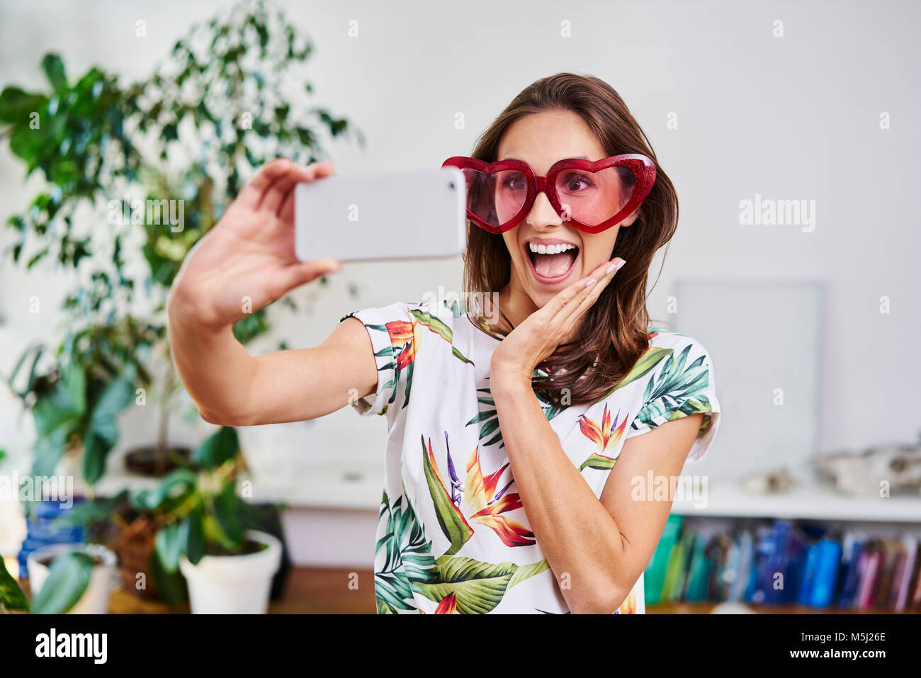 Happy young woman in heart-shaped glasses taking selfie Stock Photo - Alamy