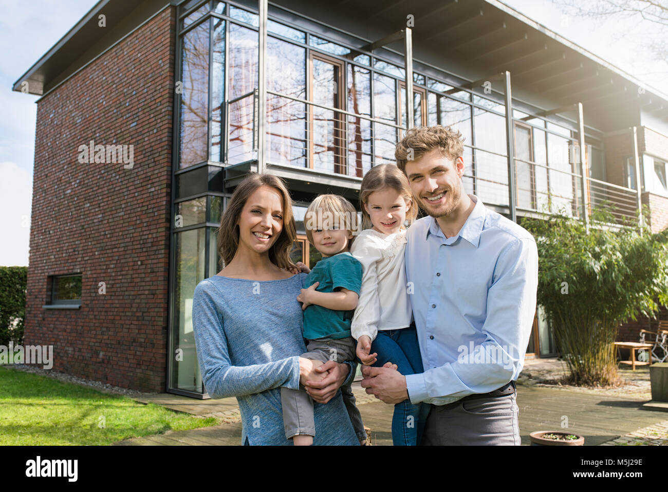 Portrait of smiling family in front of their home Stock Photo