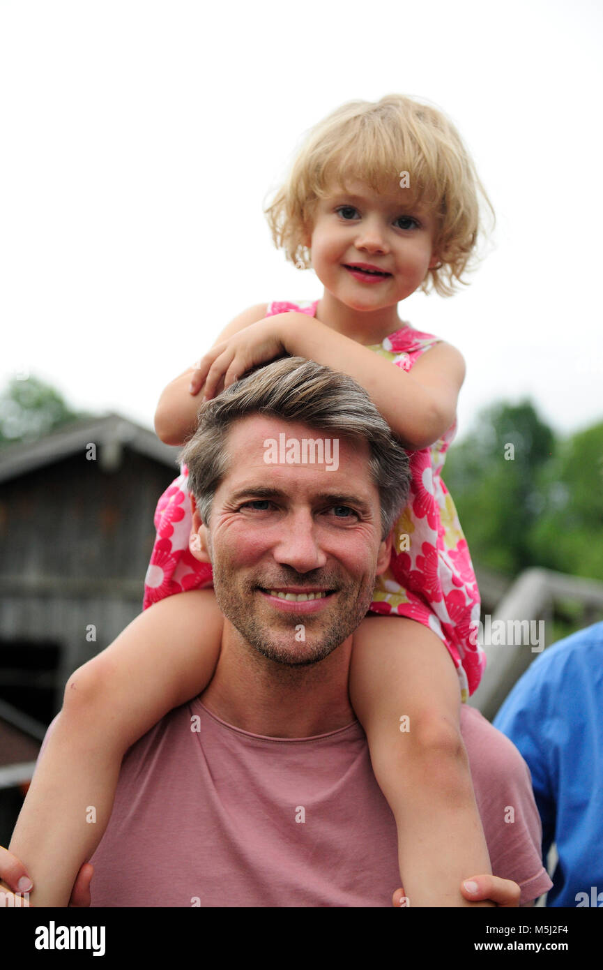 Portrait of happy man carrying his little daughter on shoulders Stock Photo
