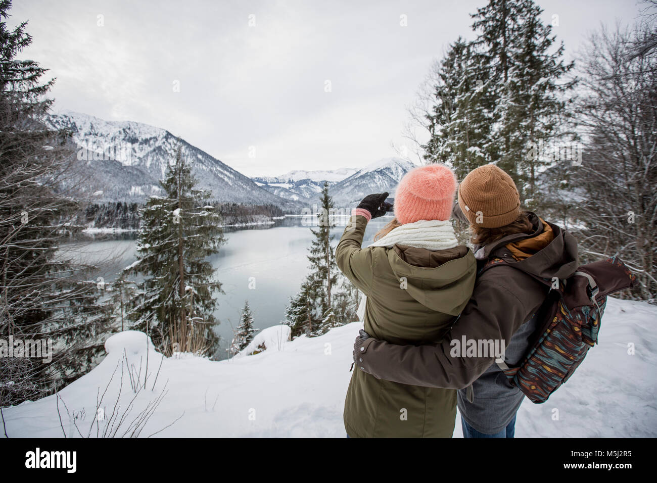 Couple taking a picture in alpine winter landscape with lake Stock Photo