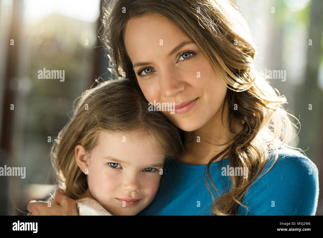 Portrait of smiling mother with daughter in front of window Stock Photo