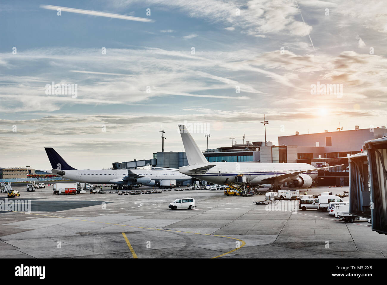 Airplanes and vehicles on the apron at sunset Stock Photo