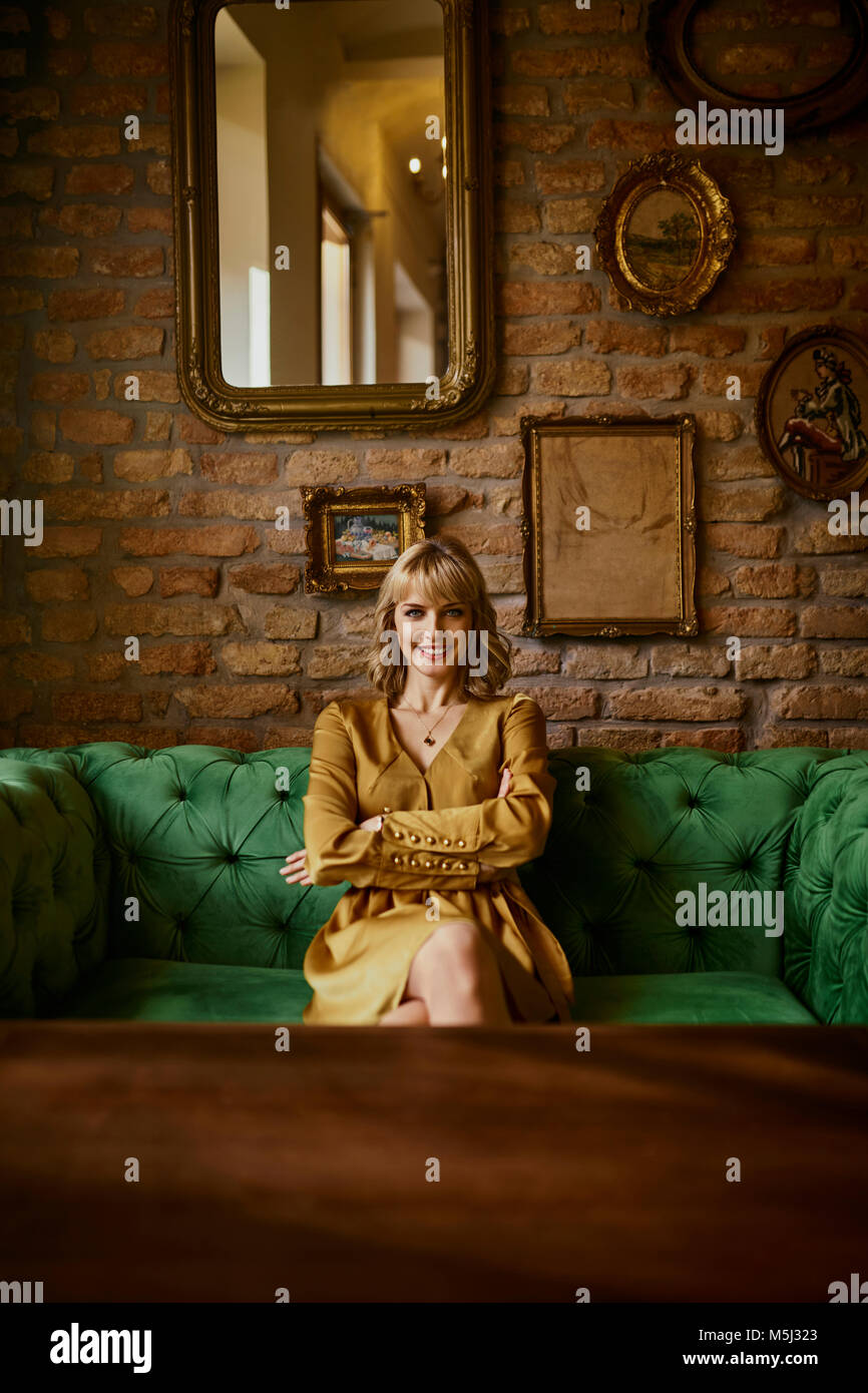 Portrait of smiling elegant woman sitting on a couch Stock Photo - Alamy