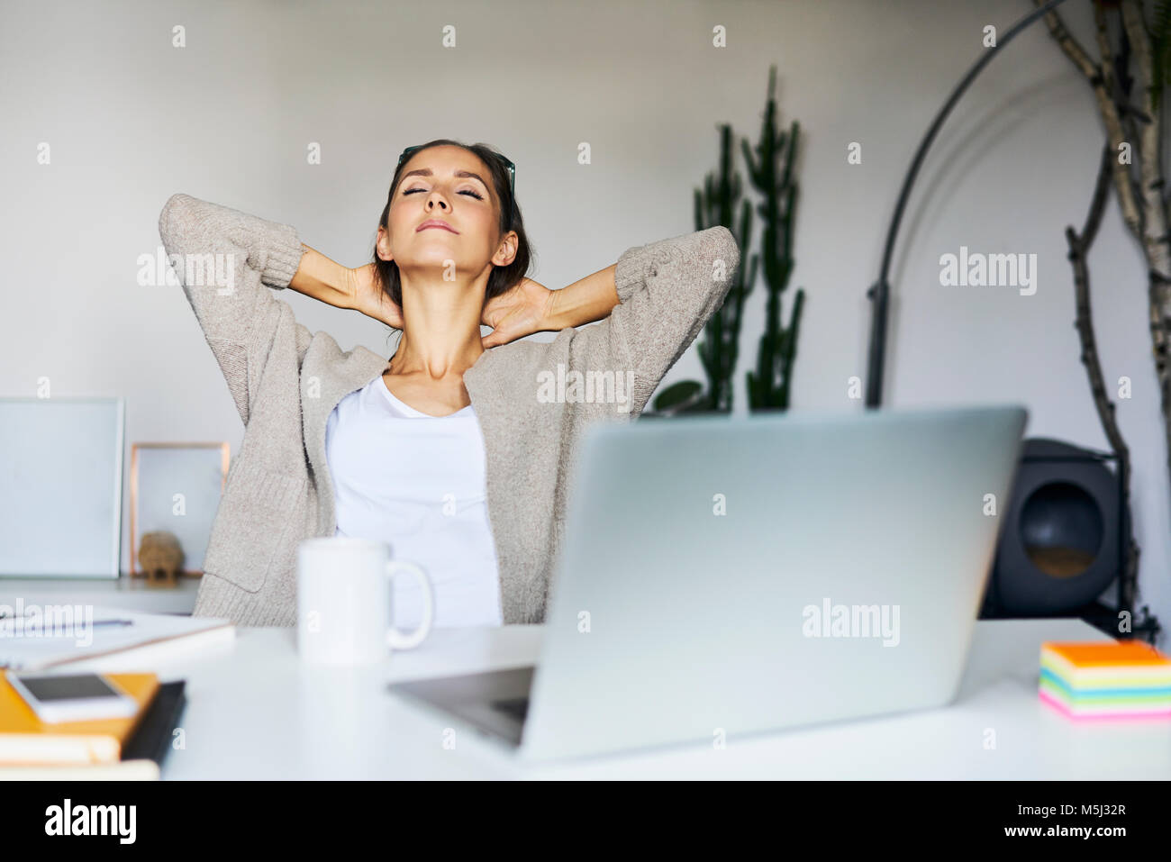 Young woman at home with laptop on desk leaning back Stock Photo Alamy